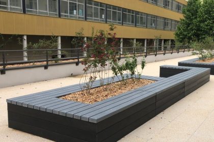 Jardinière urbaine devant bâtiment jaune.