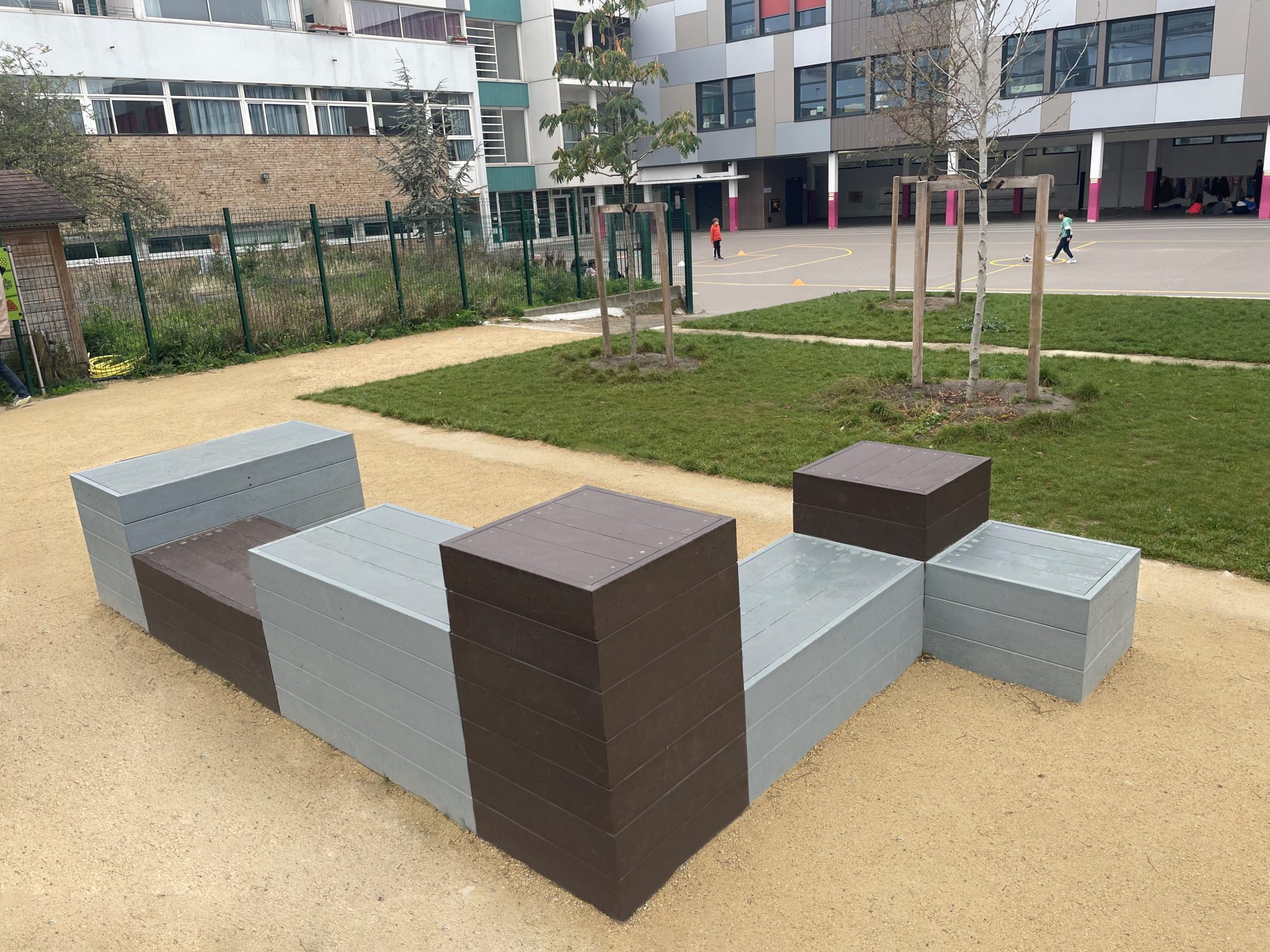 Cour d'école moderne avec bancs et verdure.