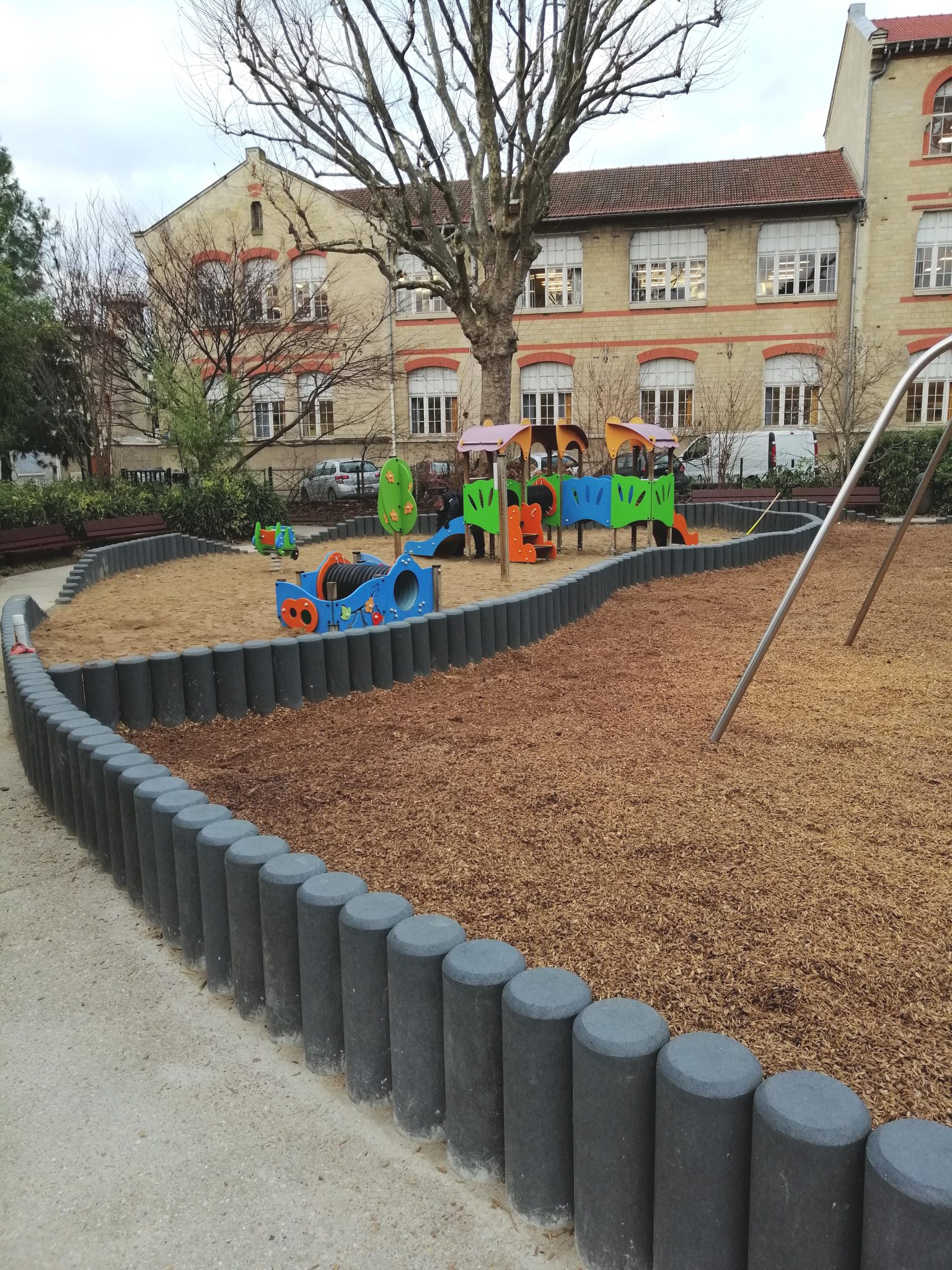 Aire de jeux enfantine extérieure, école en arrière-plan.