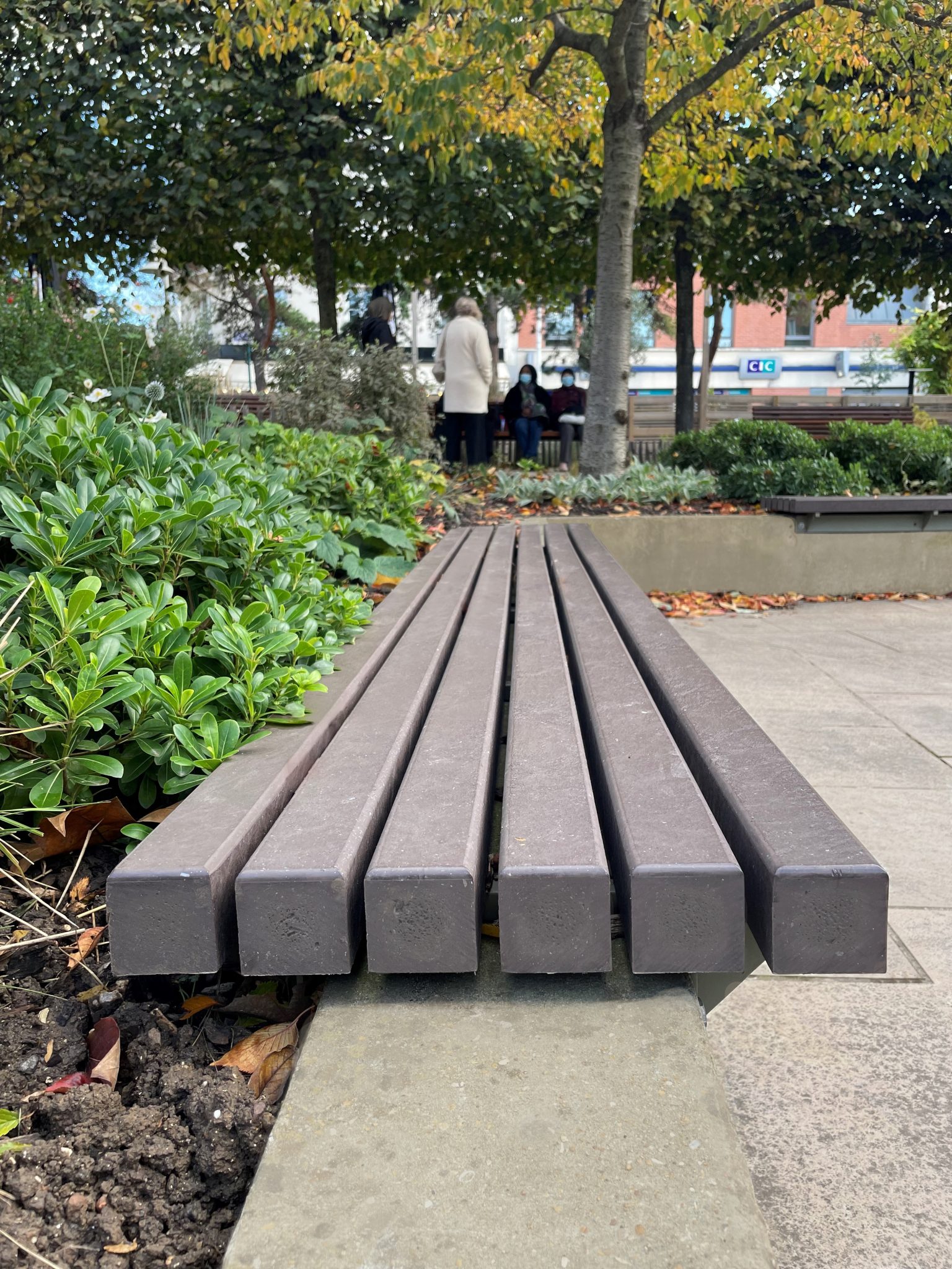 Banc public en premier plan, jardin automnal.