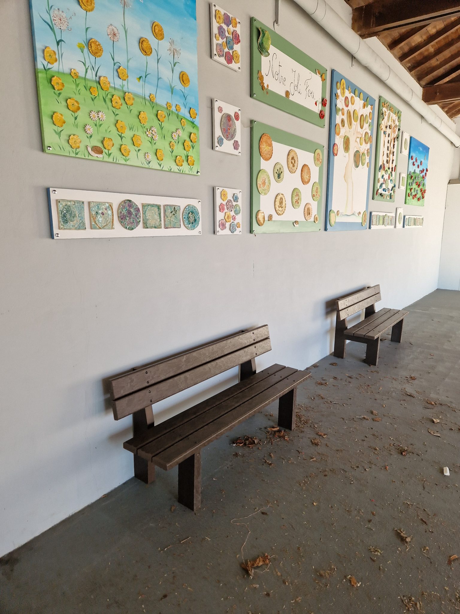 Bancs et tableaux colorés sur mur blanc.