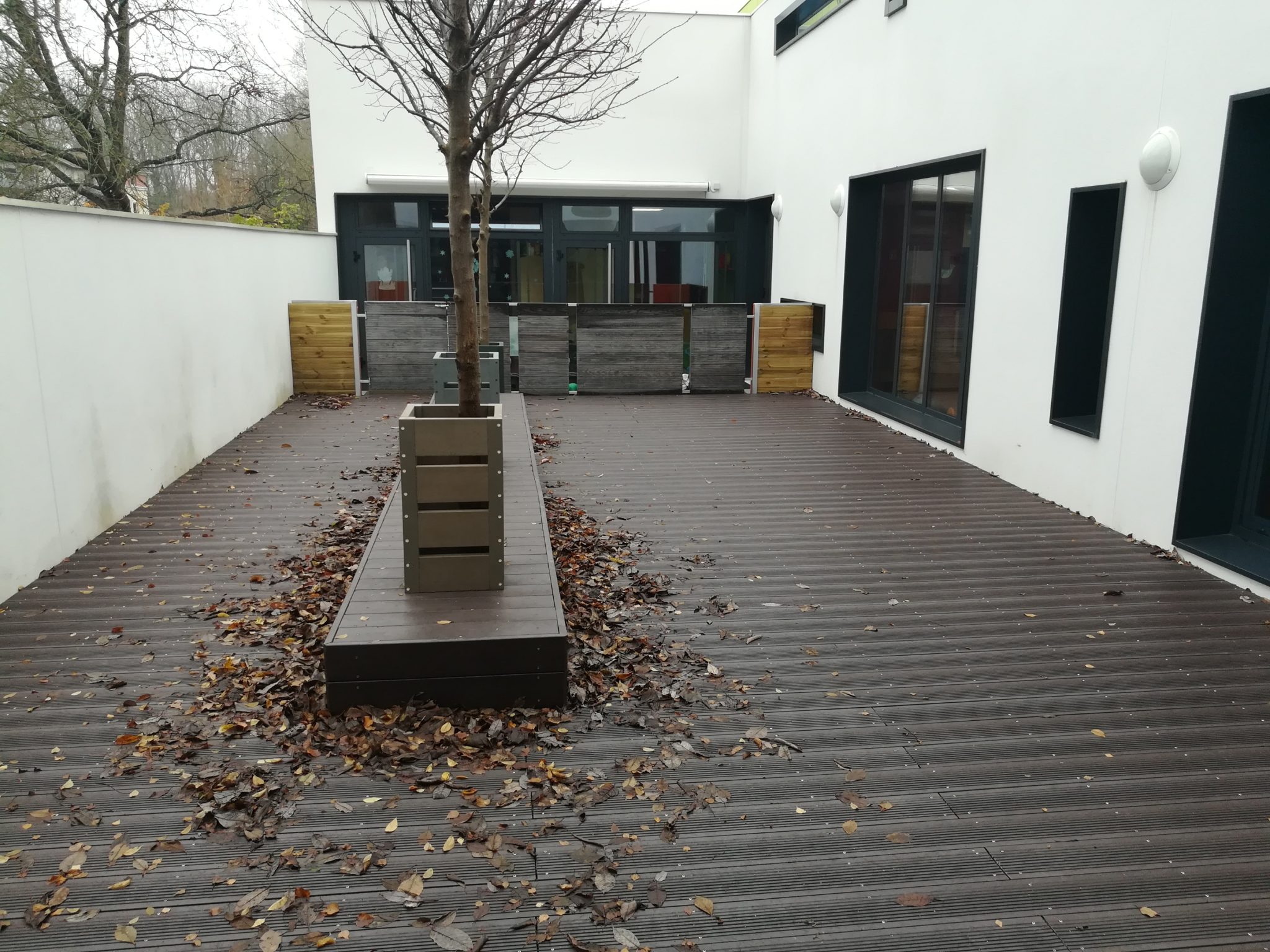 Terrasse moderne avec bancs et feuilles mortes.