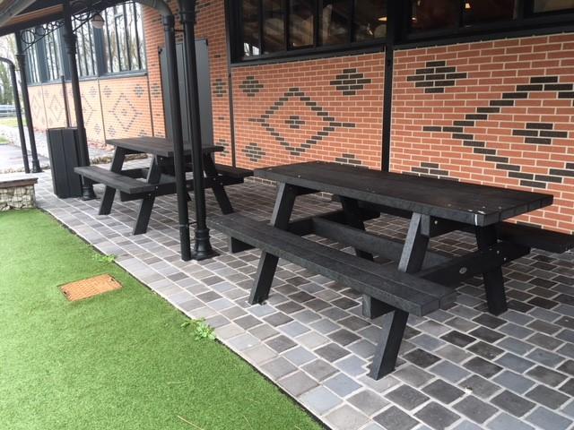 Bancs noirs en bois sur terrasse pavée.